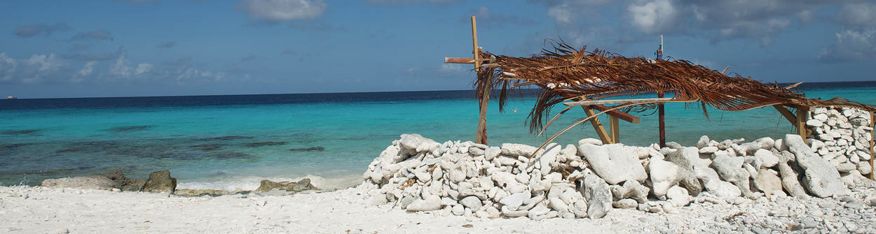 Bonaire strandhutje met witte stenen aan blauwe zee