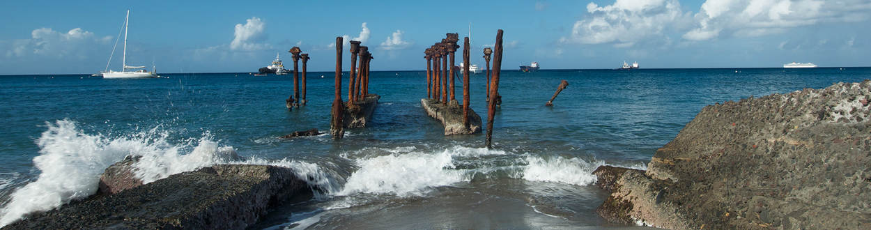Sint Eustatius oude vervallen steiger in de haven met boten op de achtegrond